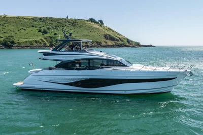 2023 Princess S72 yacht cruising on clear blue water near a lush green coastline.