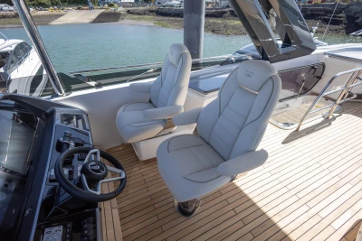 Luxury helm seats on 2023 Princess S72 yacht with sleek dashboard and wooden deck.