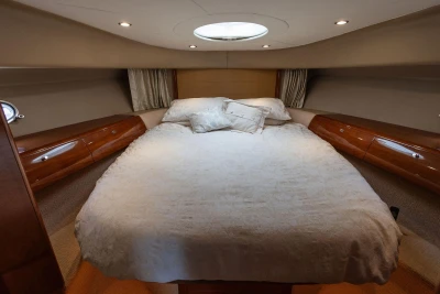 Luxurious cabin interior of a 2006 Princess V48 yacht with elegant bedding and wood accents.