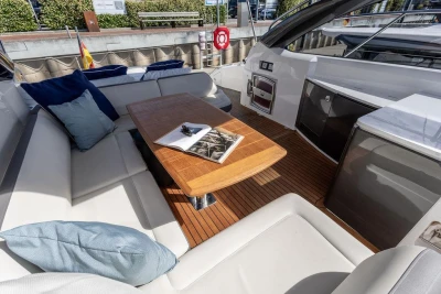 Luxurious seating area on a 2015 Princess V48 Open yacht with wooden table and cushions.