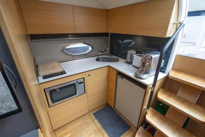 Modern kitchen in a 2015 Princess V39 yacht with appliances and wooden cabinetry.