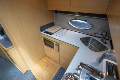 Modern galley kitchen in 2015 Princess V39 yacht with microwave, sink, and porthole window.
