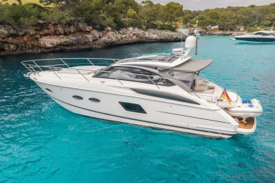 Luxury 2015 Princess V39 yacht in turquoise waters near rocky coastline.