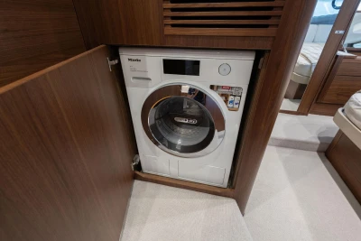 Compact Miele washer-dryer in 2024 Princess F50 yacht's wooden cabinet.