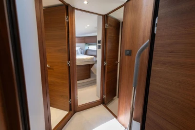 Luxurious interior of 2024 Princess F50 yacht with wooden doors and cozy bedroom.
