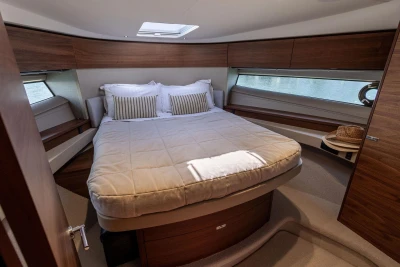 Luxurious cabin interior of 2024 Princess F50 yacht with cozy bed and elegant wood finish.
