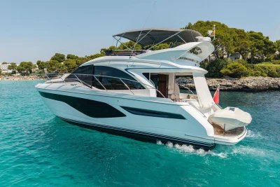 2024 Princess F50 yacht cruising in clear blue waters near a lush, green coastline.