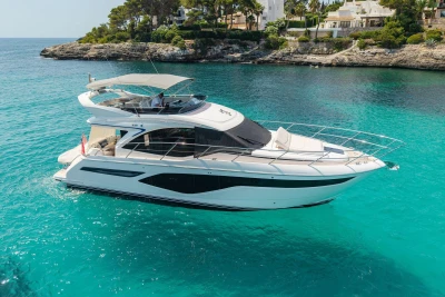 2024 Princess F50 yacht cruising in clear turquoise waters near rocky coastline.