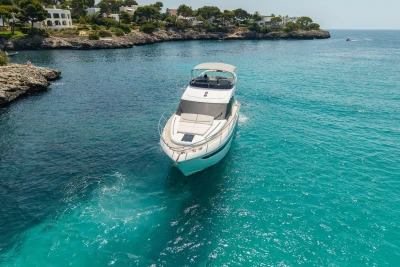 2024 Princess F50 yacht cruising in clear turquoise waters near rocky coastline.