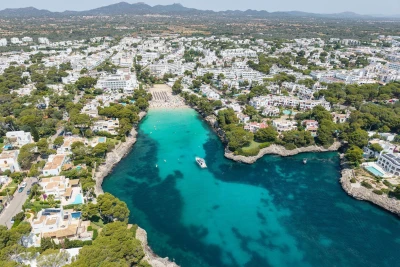 Aerial view of a coastal town with turquoise waters and lush greenery.