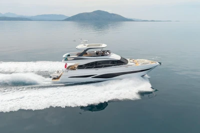 2025 Princess F65 yacht cruising on calm waters with scenic mountain backdrop.