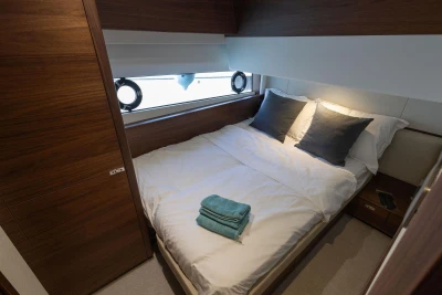 Luxurious cabin interior of 2025 Princess F65 yacht with cozy bed and elegant wood finish.