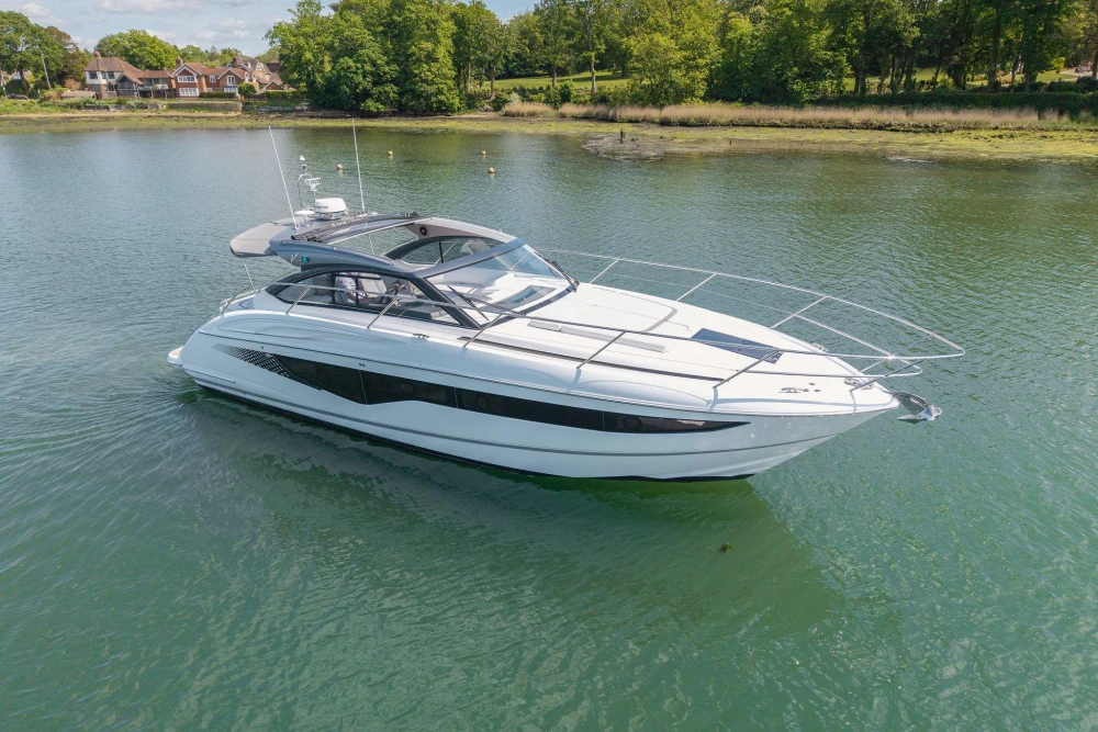2026 Princess V40 yacht cruising on a serene lake with lush greenery in the background.