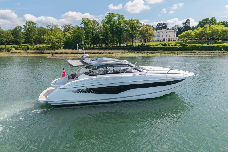 2026 Princess V40 yacht cruising on a serene lake with lush greenery in the background.