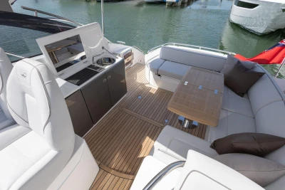Luxurious 2026 Princess V40 yacht deck with seating, table, and kitchenette by the water.