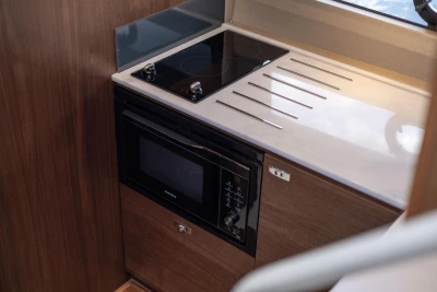 Modern kitchen area in 2026 Princess V40 yacht with stove and microwave.