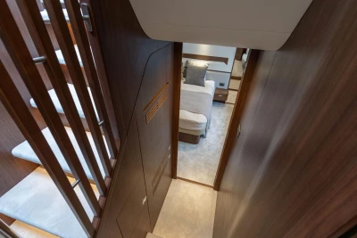 Interior view of 2026 Princess F65 yacht, featuring a cozy bedroom and elegant wooden staircase.