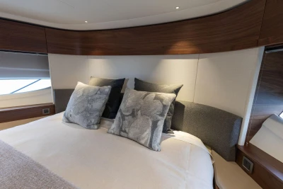 Luxurious bedroom interior of 2026 Princess F65 yacht with elegant pillows and wood accents.