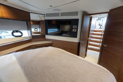 Luxurious interior of 2026 Princess F65 yacht with modern wood finishes and cozy bedding.