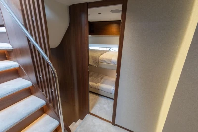 Luxurious interior of 2026 Princess F65 yacht with wooden stairs and cozy bunk beds.