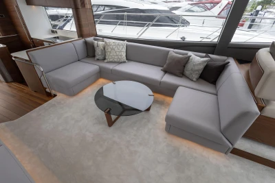 Luxurious interior of 2026 Princess F65 yacht with modern gray seating and glass table.