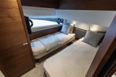Luxurious twin cabin interior of 2026 Princess F65 yacht with modern wood finish.