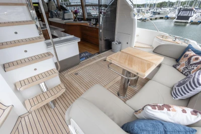 Luxurious 2020 Princess F55 yacht interior with elegant seating, wooden table, and marina view.