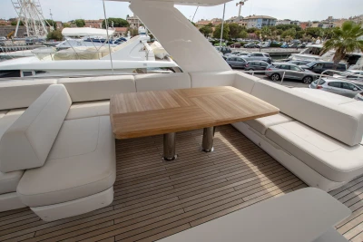 Deck area with a wooden table and white sofas on a yacht.
