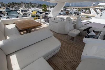 The image shows the deck of a luxury yacht with white seating and a wooden table.
