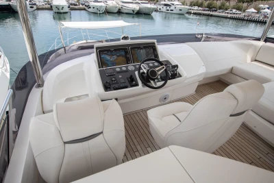 The image shows the cockpit of a luxury yacht with modern navigation systems and comfortable seating.