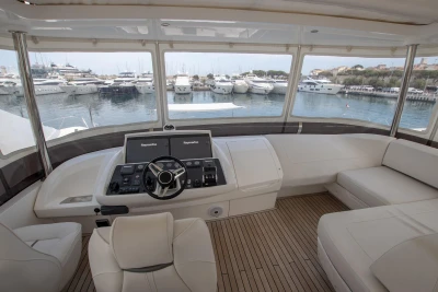 Interior view of a luxury yacht with white seating and a harbor view.