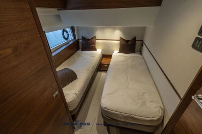 Luxurious twin cabin interior of 2026 Princess S65 yacht, featuring elegant wood finishes.