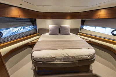 Luxurious cabin interior of 2026 Princess S65 yacht with elegant wood finishes and cozy bedding.
