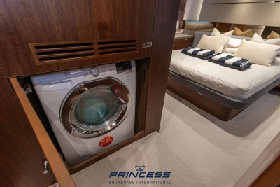 Luxury yacht interior with washing machine, cozy bedroom, and elegant wood finish, Princess S60 2019.