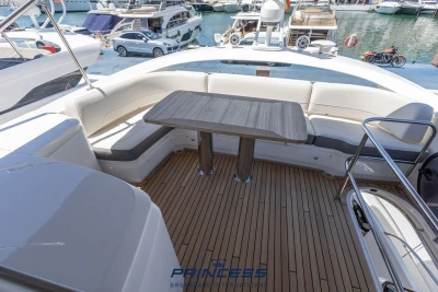 Luxurious 2019 Princess S60 yacht deck with elegant seating and table, docked at marina.