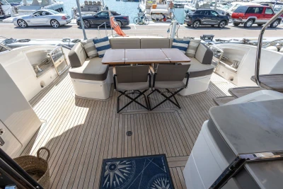 Luxury yacht deck with seating area, table, and marina view; Princess S60, 2018 model.