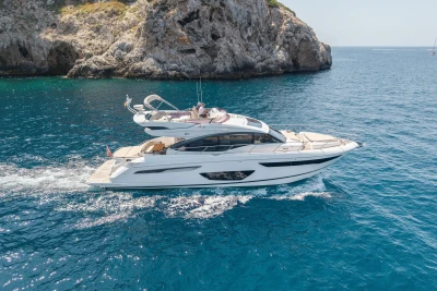 Luxury 2018 Princess S60 yacht cruising near rocky coastline in clear blue waters.