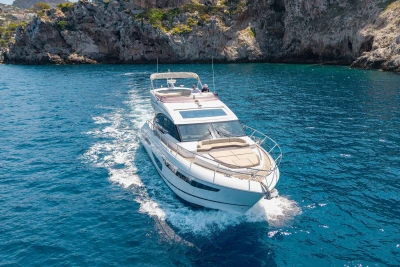 Luxury 2018 Princess S60 yacht cruising in clear blue waters near rocky cliffs.