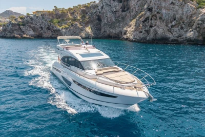 Luxurious 2018 Princess S60 yacht cruising near rocky coastline in clear blue waters.