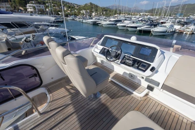 Luxurious 2018 Princess S60 yacht helm with modern controls, docked in a scenic marina.