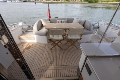 The 2022 Princess F55 features an elegant aft deck with wooden flooring, a table, and comfortable seating.