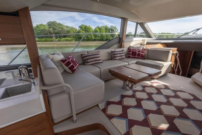 The interior of a luxury yacht with a large, comfortable sofa and a wooden table.