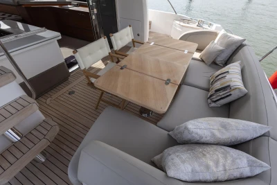 The image shows the deck of a 2022 Princess F55 yacht with elegant seating and a wooden table.