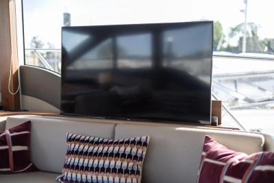Interior of a yacht featuring a large TV and decorative pillows on the sofa.