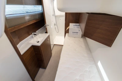 Interior of a modern yacht with a single bed, sink, and shower, stylishly and functionally designed.