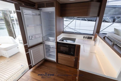 Modern kitchen interior of 2025 Princess F50 yacht with open fridge and sleek design.