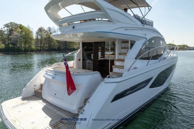 Luxury Princess F50 yacht, 2025 model, docked on serene water with lush greenery.