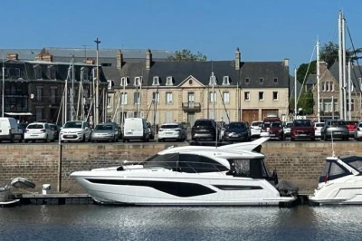 Luxury Princess F50 yacht docked in a marina, 2025 model, with historic buildings in the background.