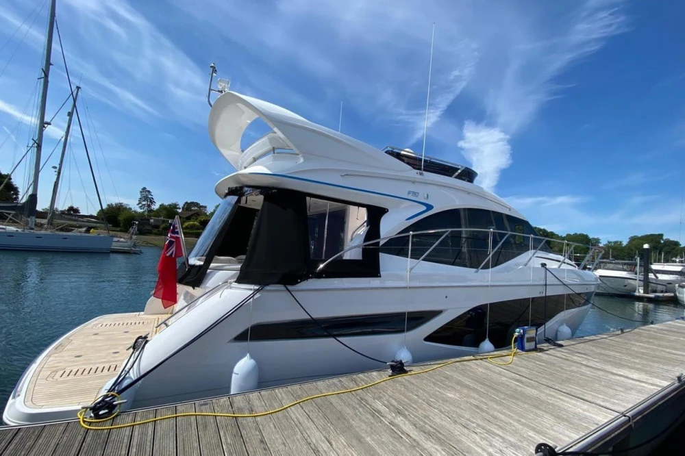 Luxury 2025 Princess F50 yacht docked at marina under clear blue sky.