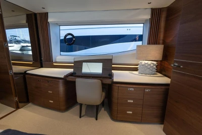 Luxurious interior of 2026 Princess X80 yacht with elegant wood furnishings and large window.